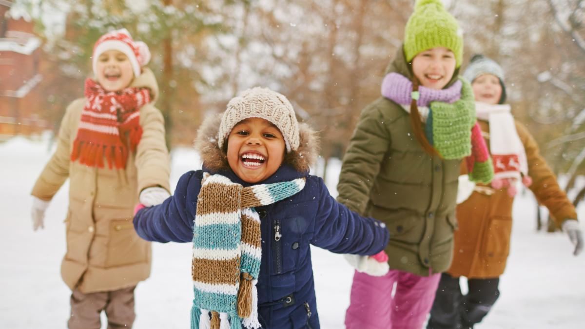 A small group of elementary age children playing happily in the snow
