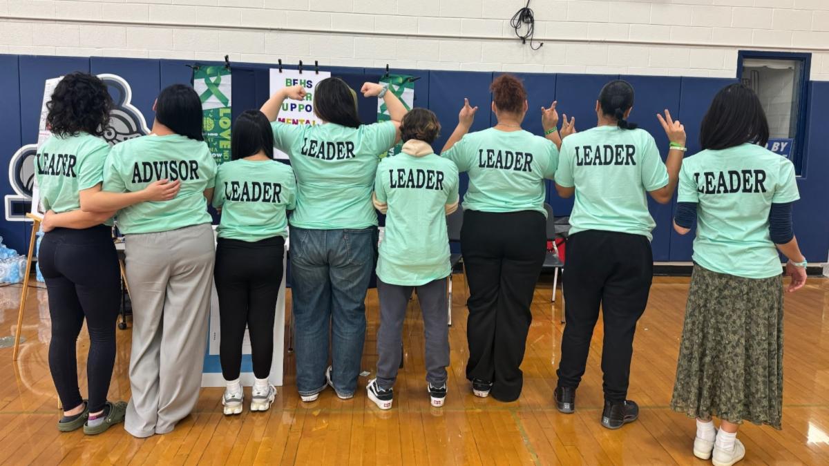 The Bristol Eastern High School peer support team poses together with backs to camera showing their "leader" T-Shirts