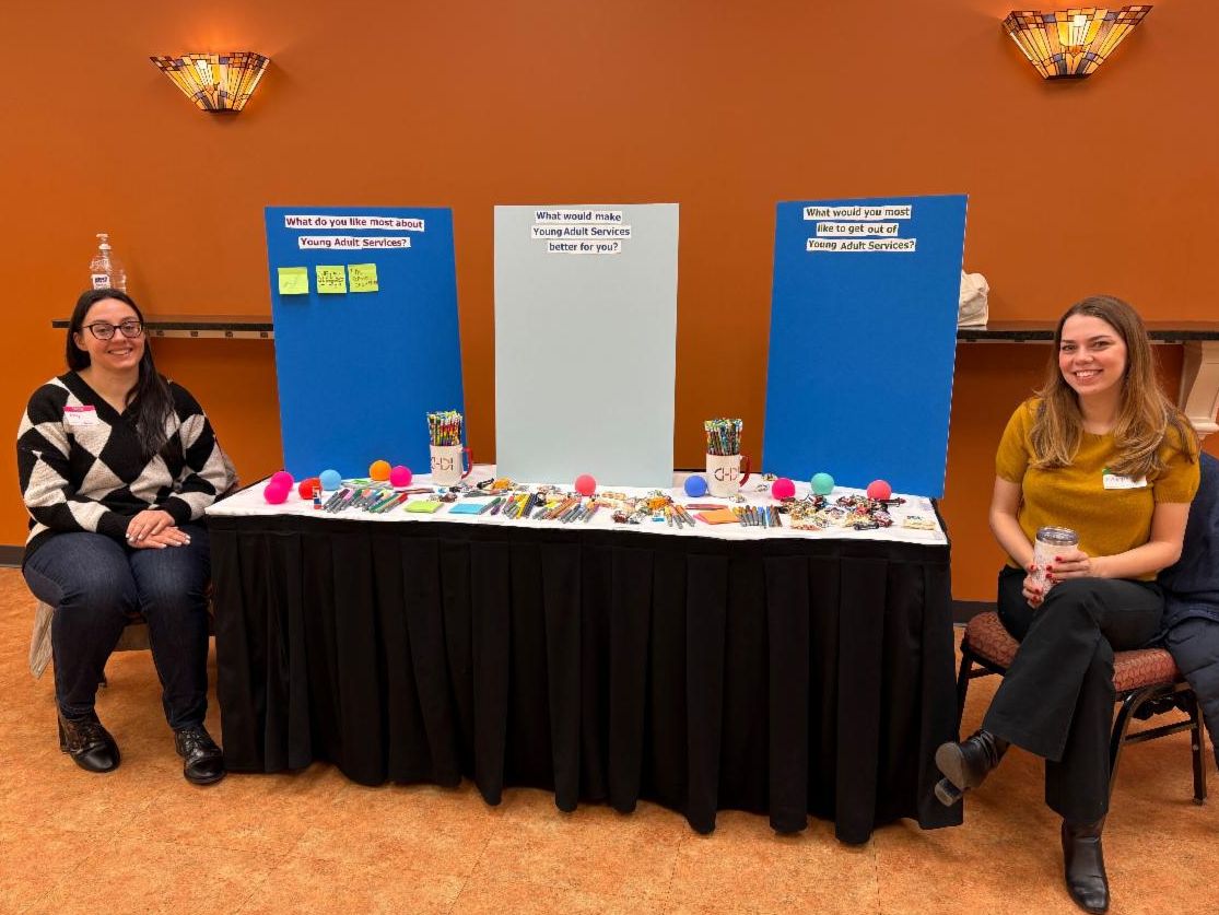 CHDI staff seated at information table at YAS Young Adult Leadership Summit
