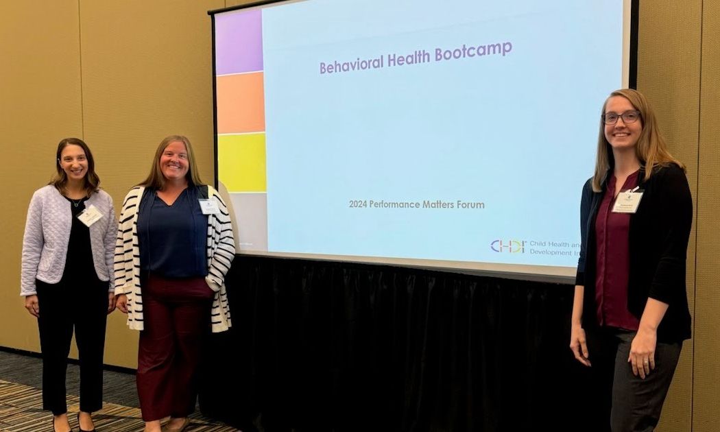 3 CHDI staff pose in front of projector screen at their presentation