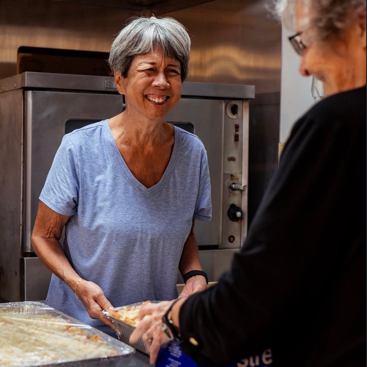 Patti and Laura smile while preparing food