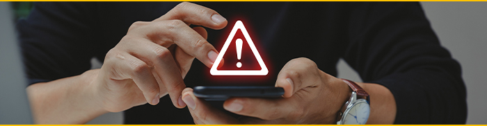 A person holding a phone with a red exclamation mark hovering over the phone