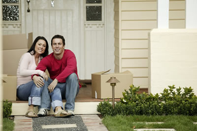 A couple sitting on a front porch with moving boxes