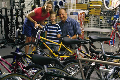 A child with parents standing with a yellow bike in a bike shop