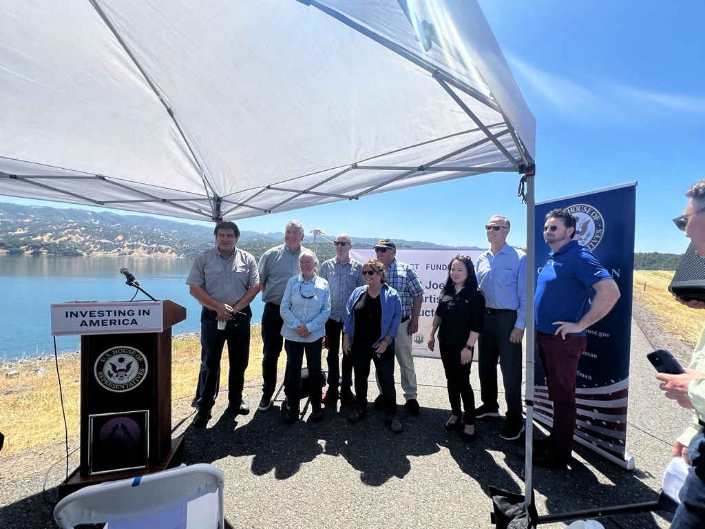 group photo in front of a lake under a shade canopy