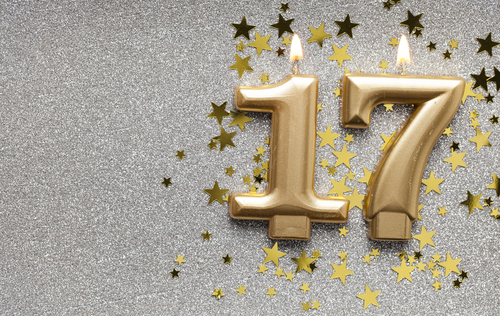 Number 17 gold celebration candle on star and glitter background