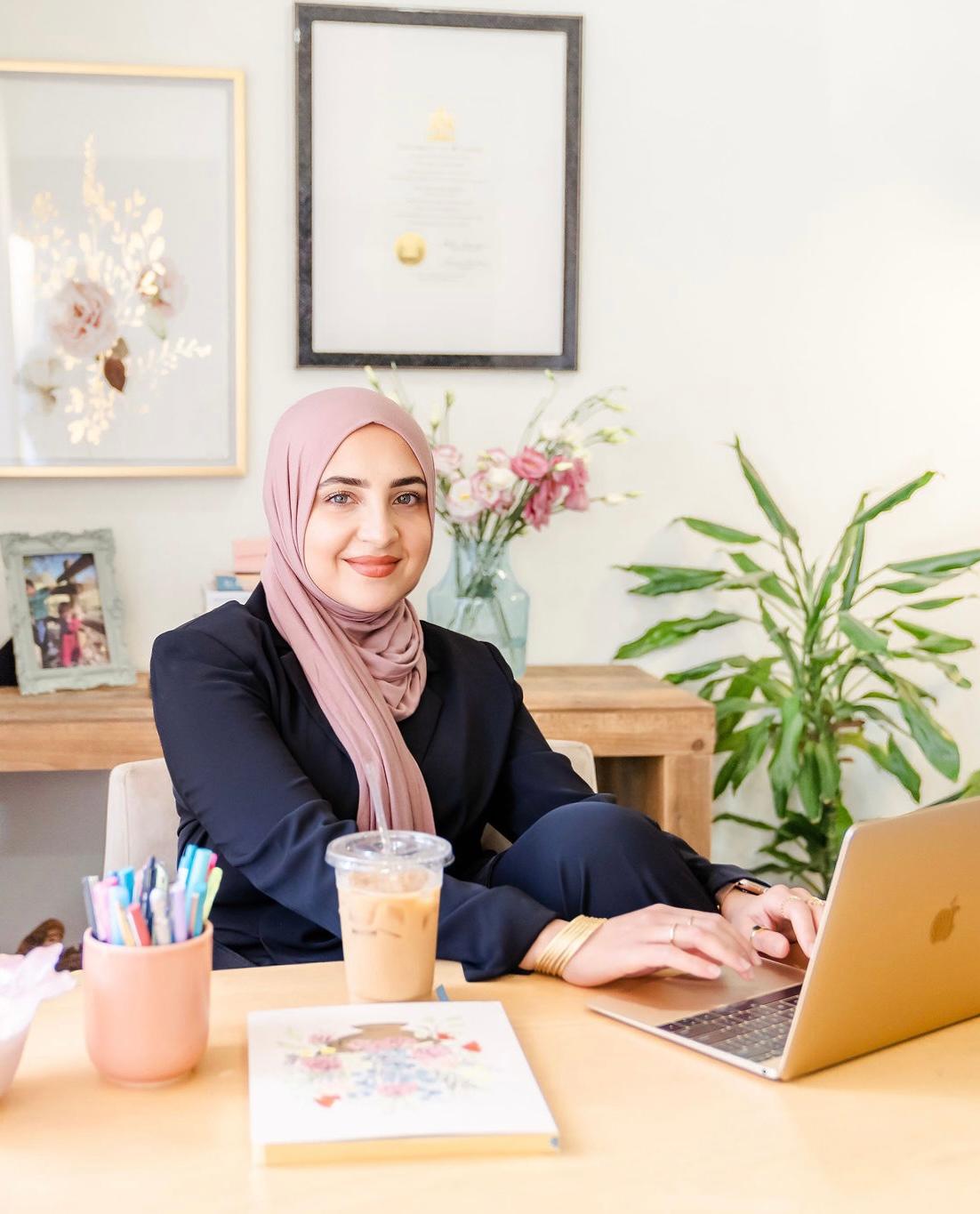 a WOMAN SITTING AT A TABLE WITH A LAPTOP