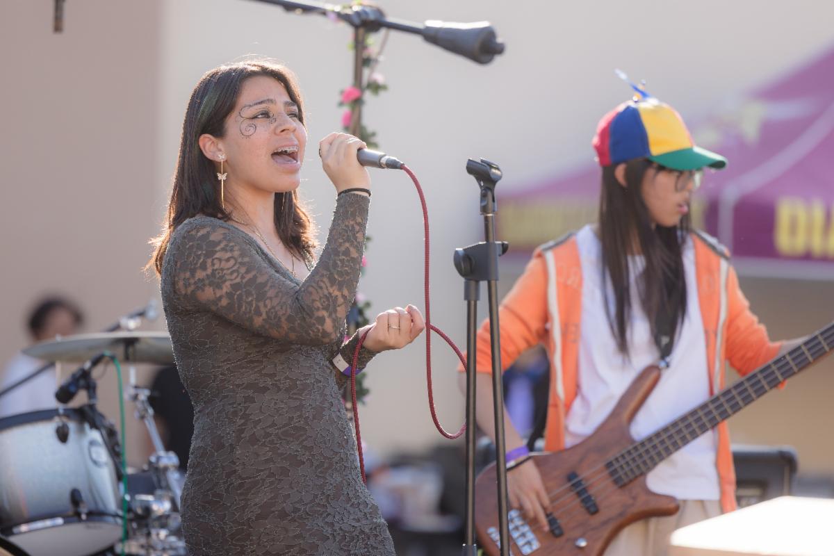 Student singing into a microphone as part of a band performance