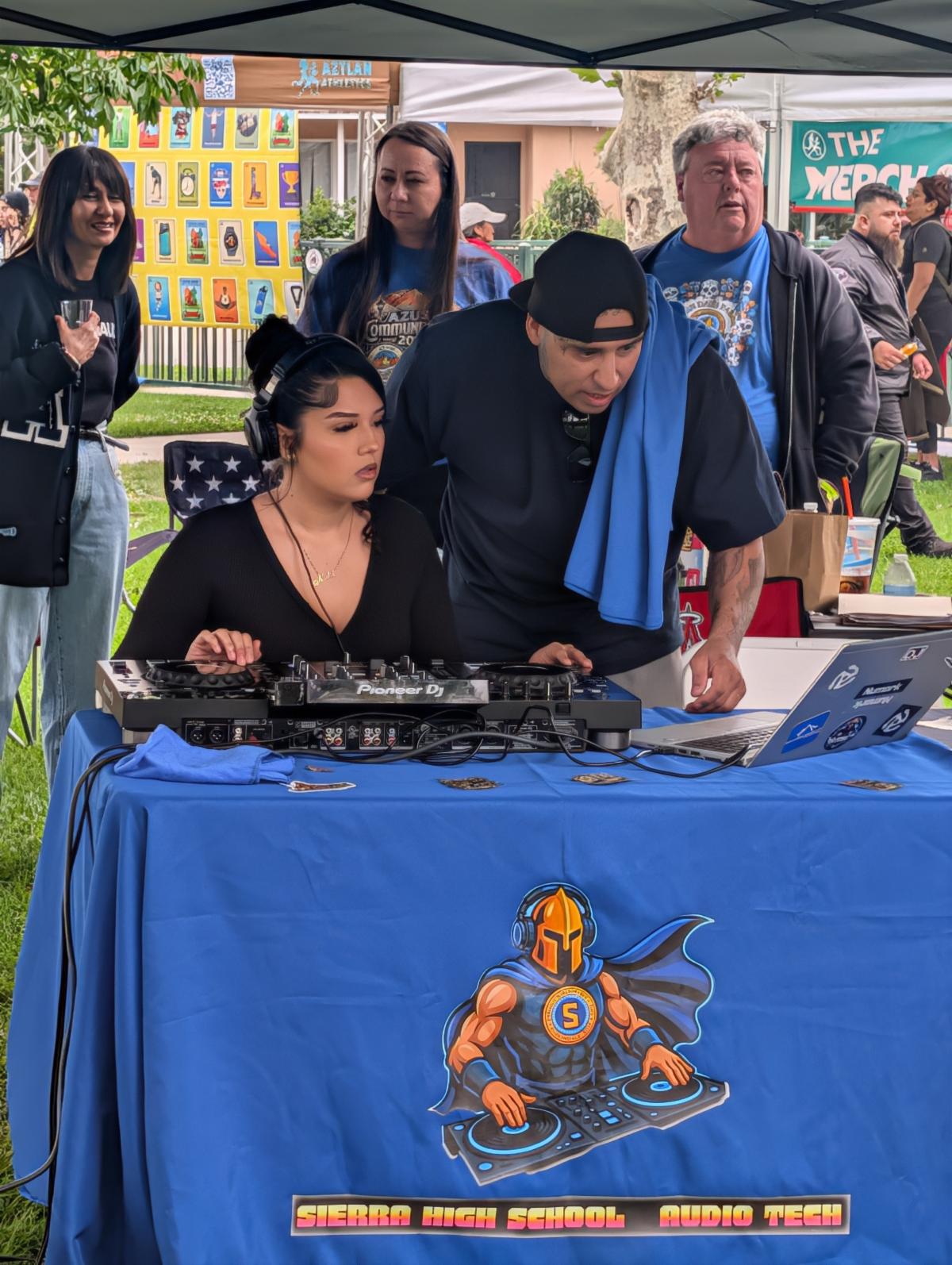 Student and teacher working with a computer while Dj'ing