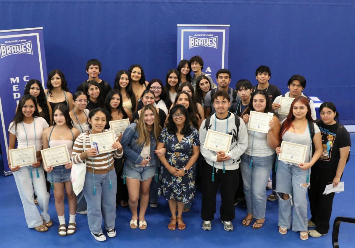 A large group of students posing in front of a cloth background smiling. 