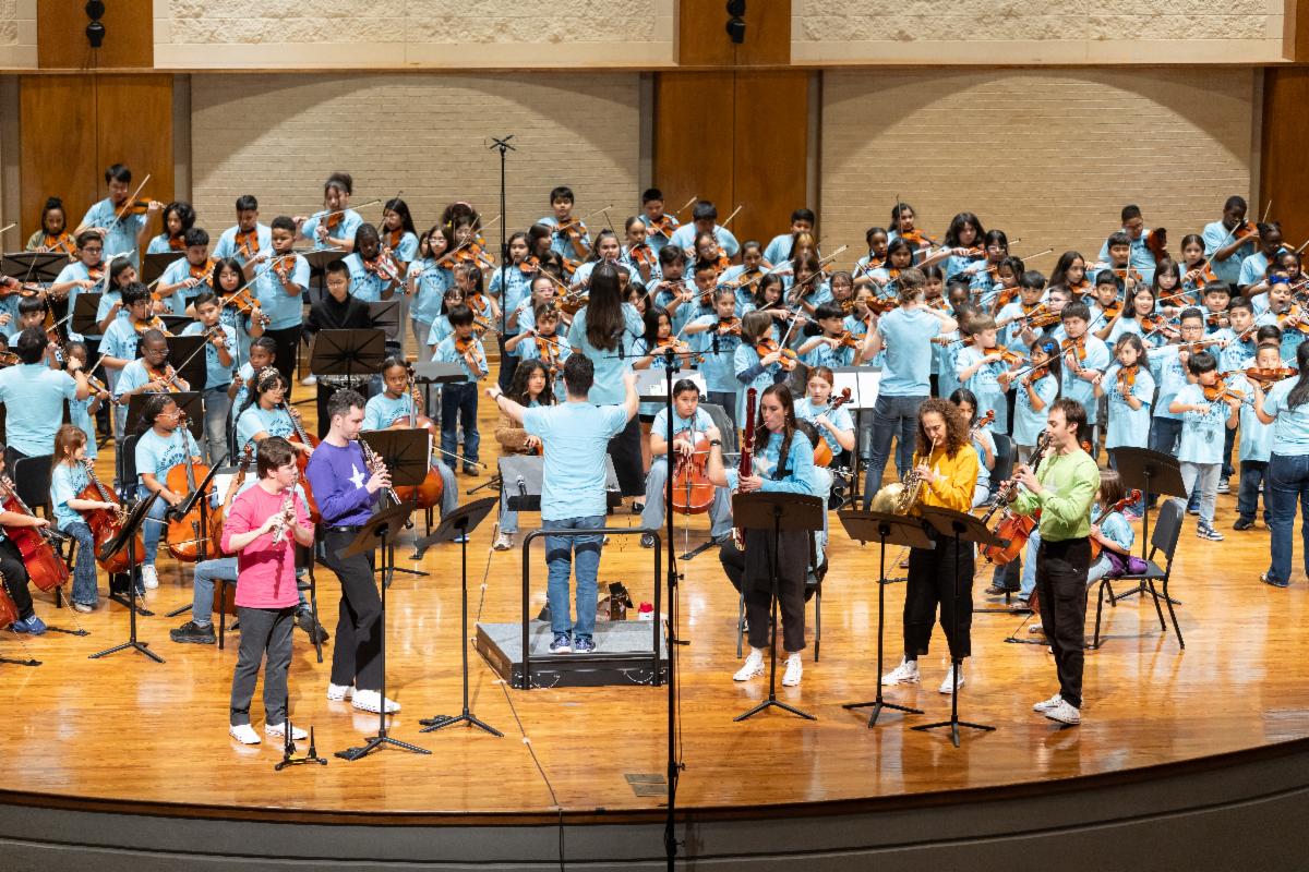 A photo of the Houston Youth Symphony performing on stage with a guest wind quintet.