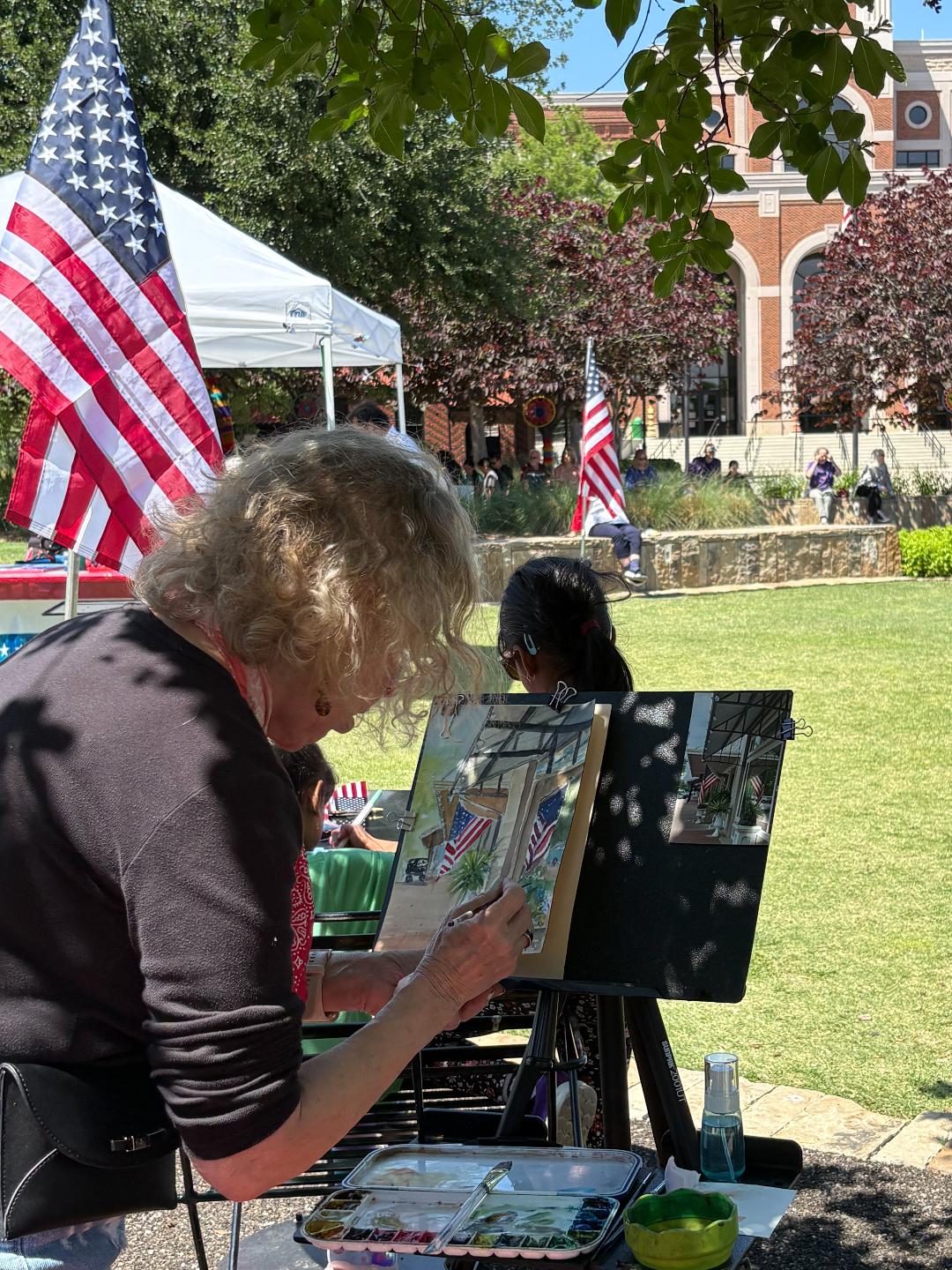 A person does some plein air painting of the America250 event.
