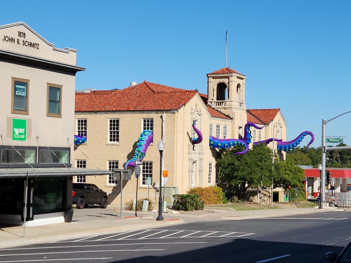 A two-story building features large blue and purple tentacles coming from the windows.