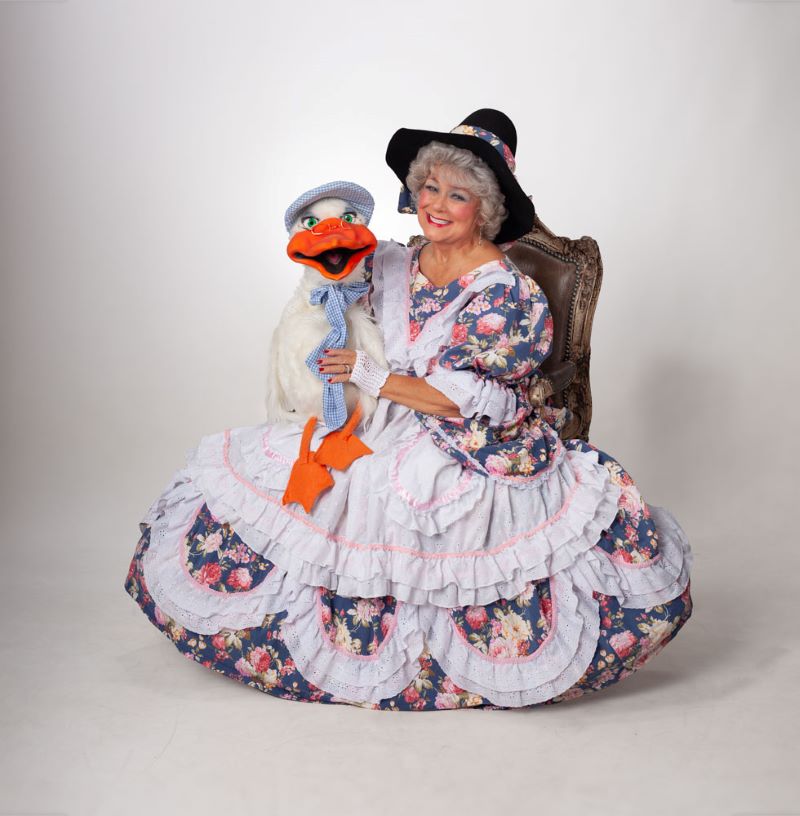 Margaret Clauder is dressed as mother goose and holds a goose puppet