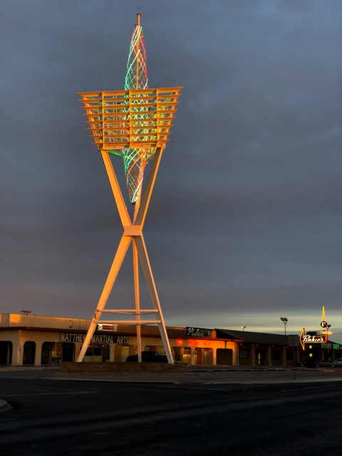 A large spire glows over the Odessa Cultural District at sunset. Smaller structures are seen around it.