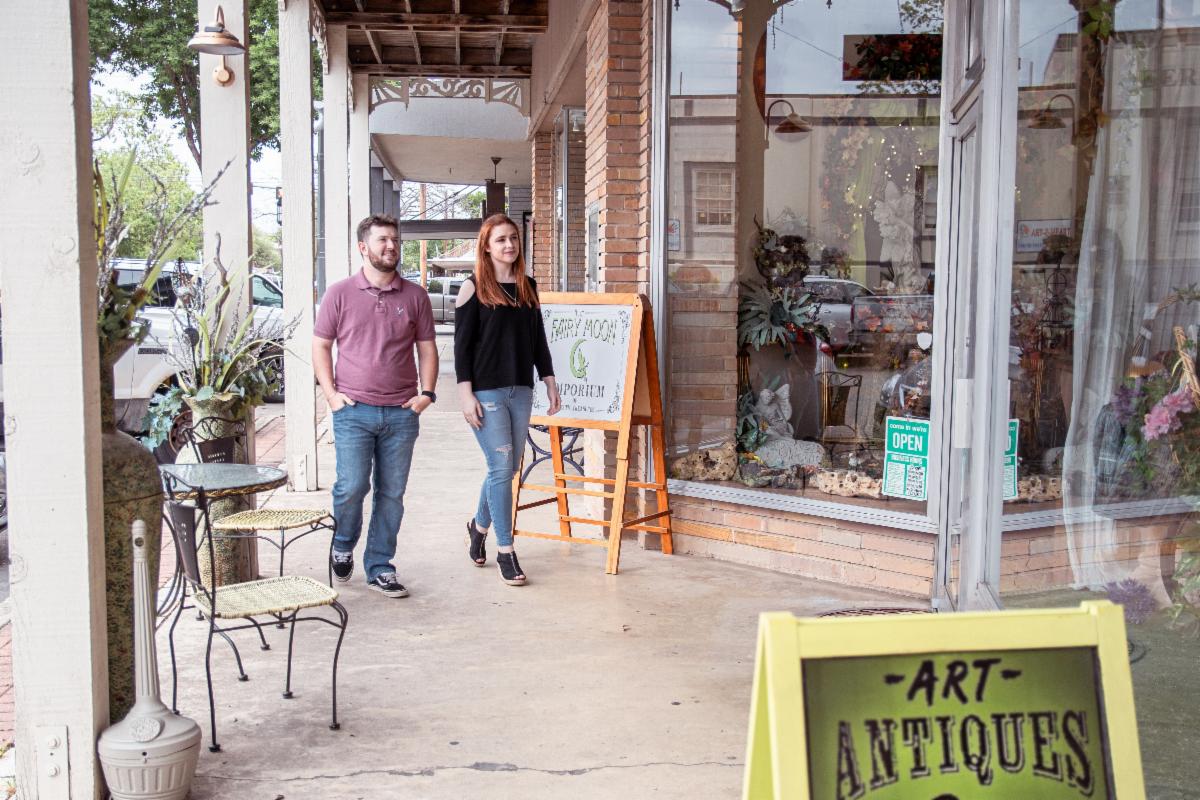 Two people stroll beside boutique windows in downtown Kerrville