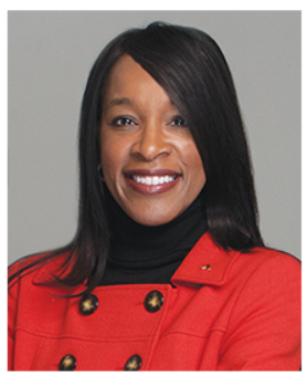 A headshot of TCA Commission Chair Karen Partee. She smiles broadly at the camera. Her straight black hair sweeps across her right eye. She wears a red jacket over a black turtleneck.