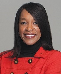 Chair Partee smiles at the camera and wears a double-breasted red jacket. Her sleek dark hair sweeps over her left eye.