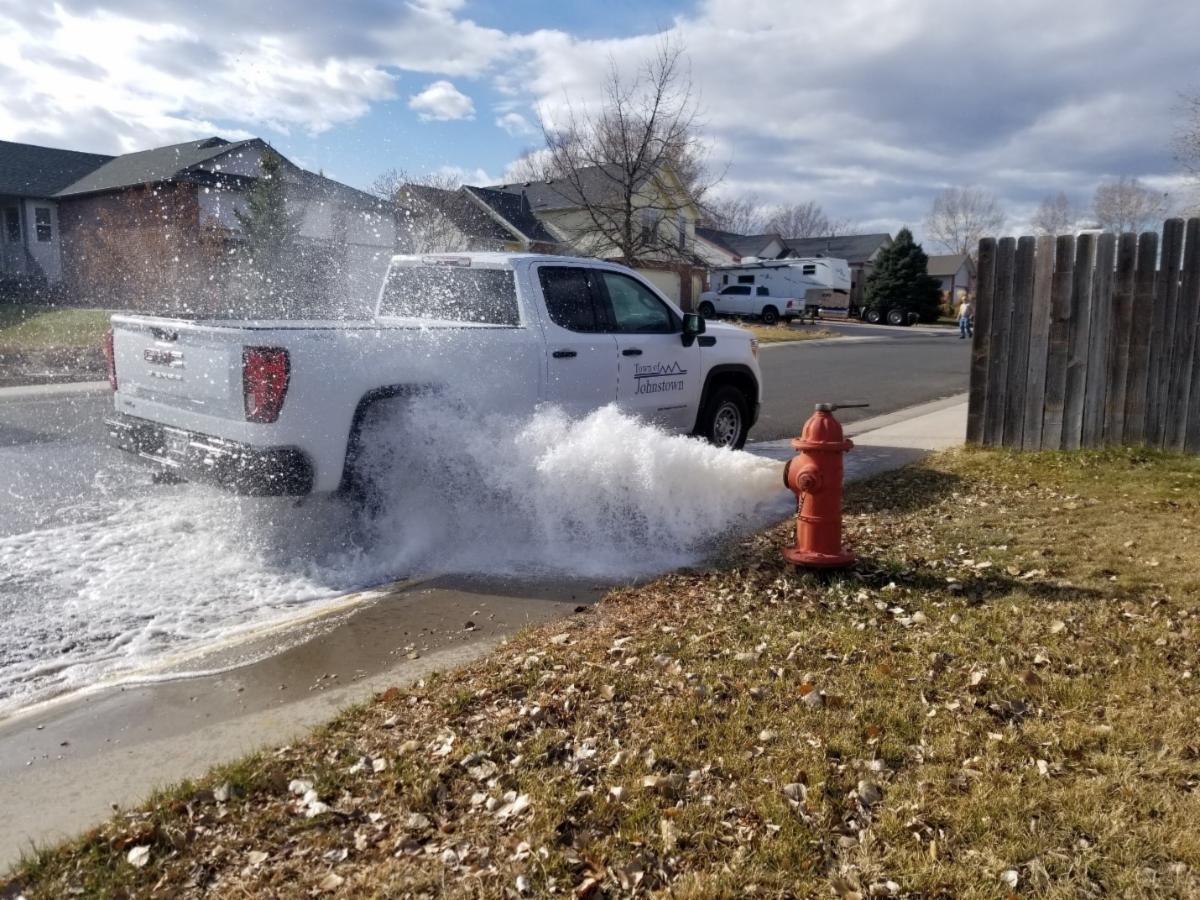 A water hydrant spraying into the side of a Town of Johnstown Truck for hydrant flushing. 