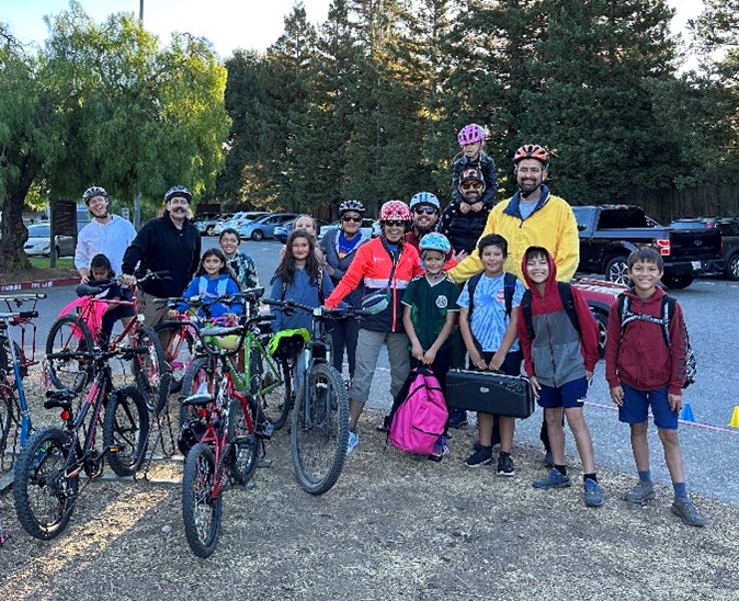 A group of school-aged children and parents biking and walking to school.