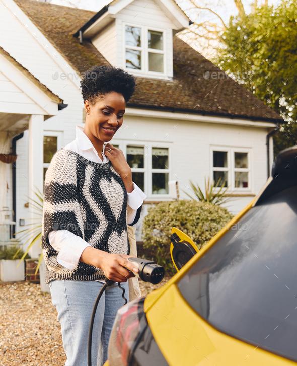 Woman smiling while outside charging yellow electric vehicle