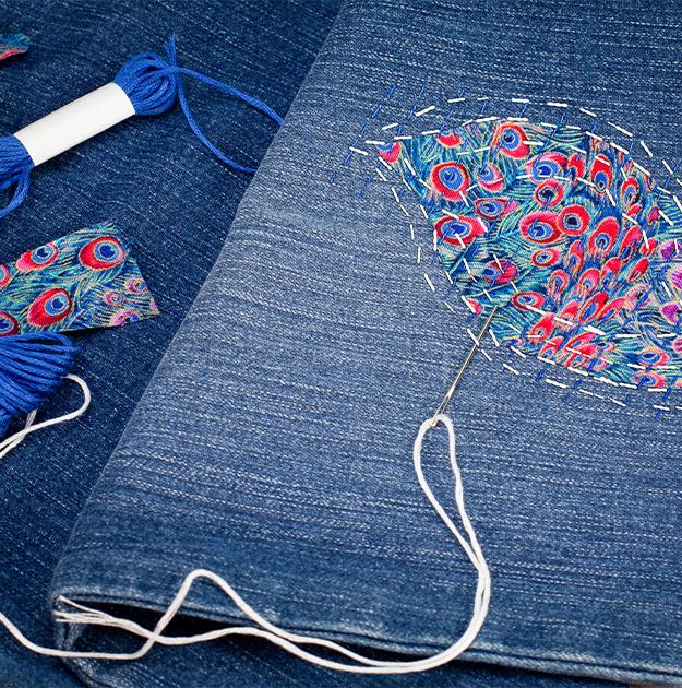 pair of jeans with colorful embroidery that repairs a hole from wear
