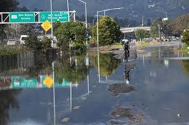 A flooded roadway with a cyclist navigating through standing water