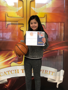 Female student holding certificate and basketball