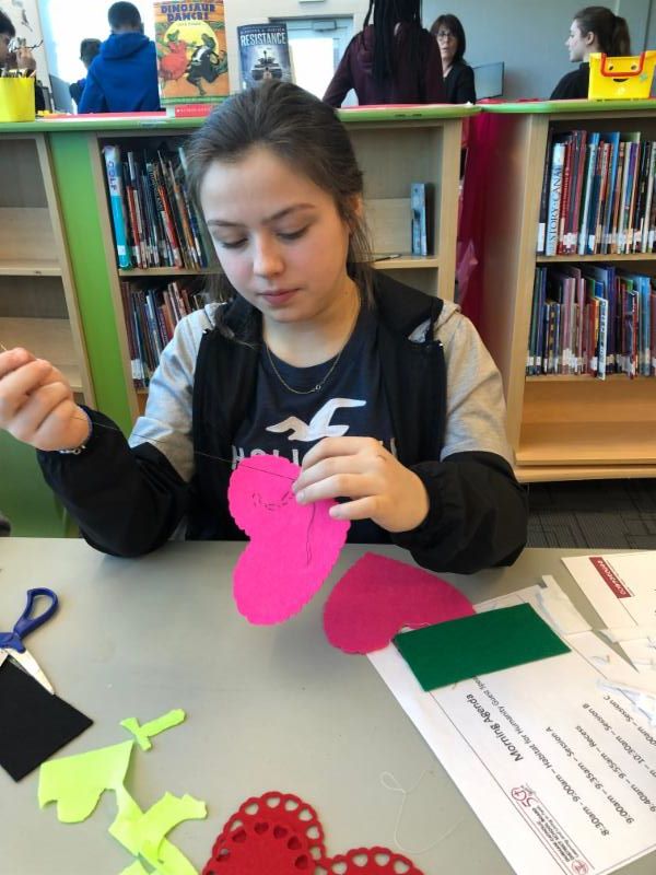 Female student sewing a heart shape pillow.