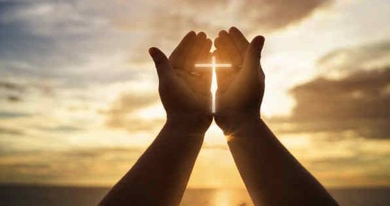 Hands together in the sky with cross between hands