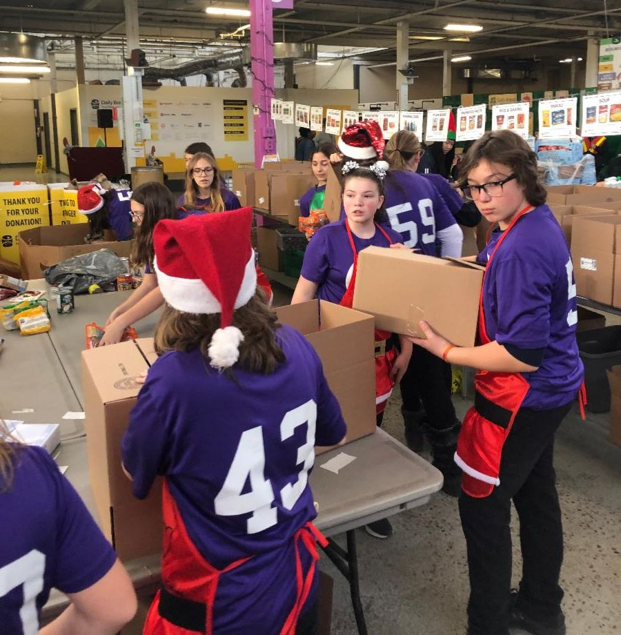 Female students working together to sort boxes of food.