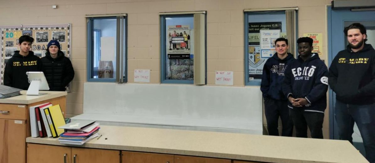 Five male student standing beside the bench they built and installed