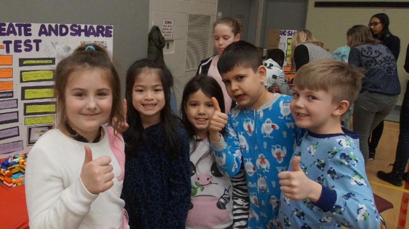 Female and male students give a thumbs up to the Lego Robotics projects.
