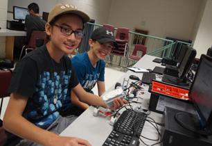 Two male students programming a robot in a computer lab
