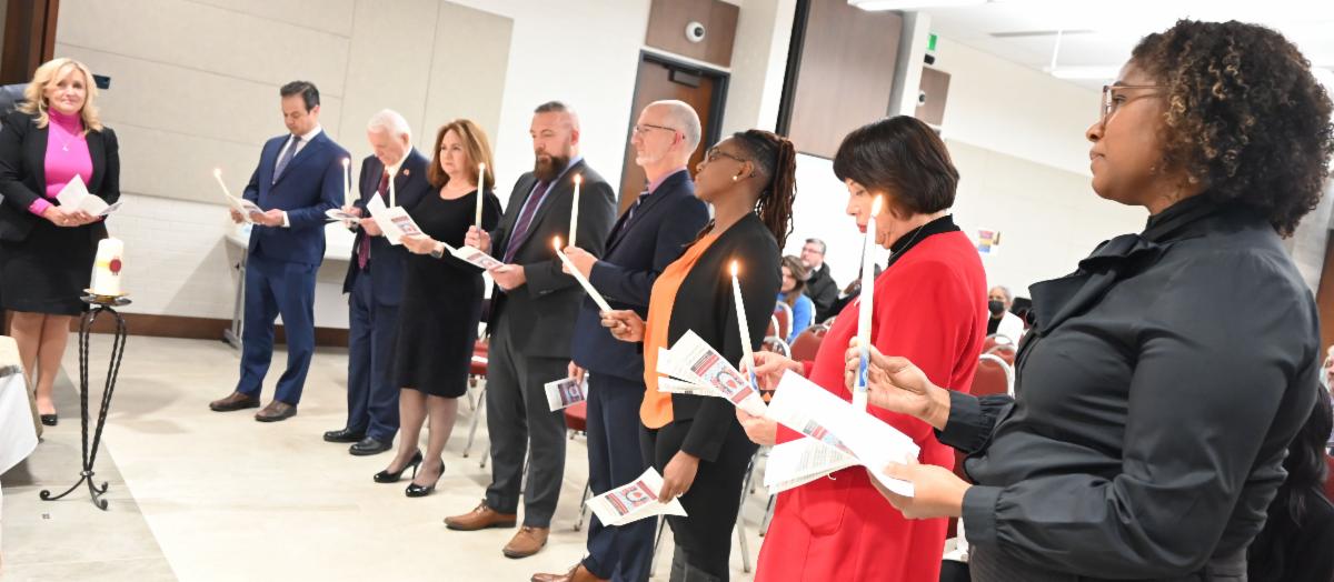 Trustees standing with lit candle during dedication of service ceremony