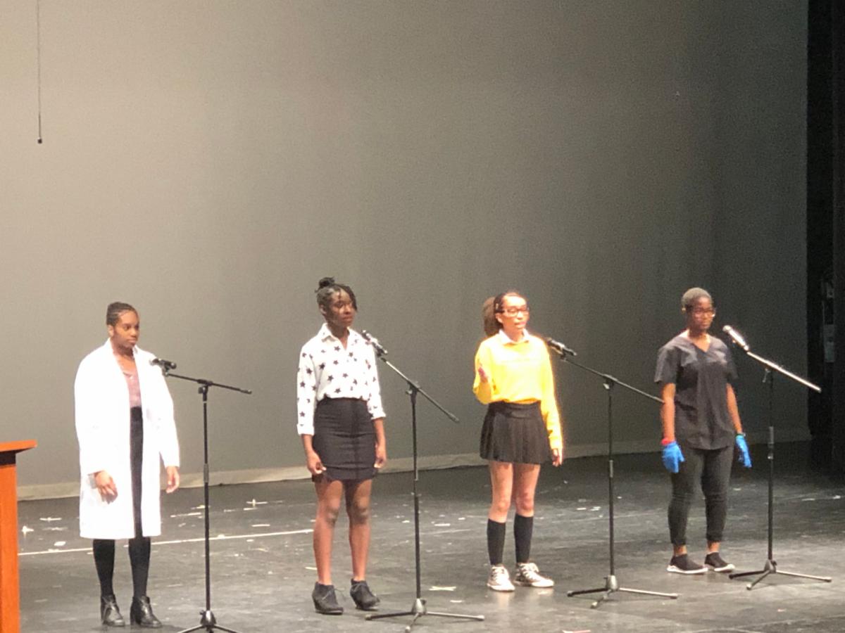 Four female students performing poetry on stage for Black History Month.