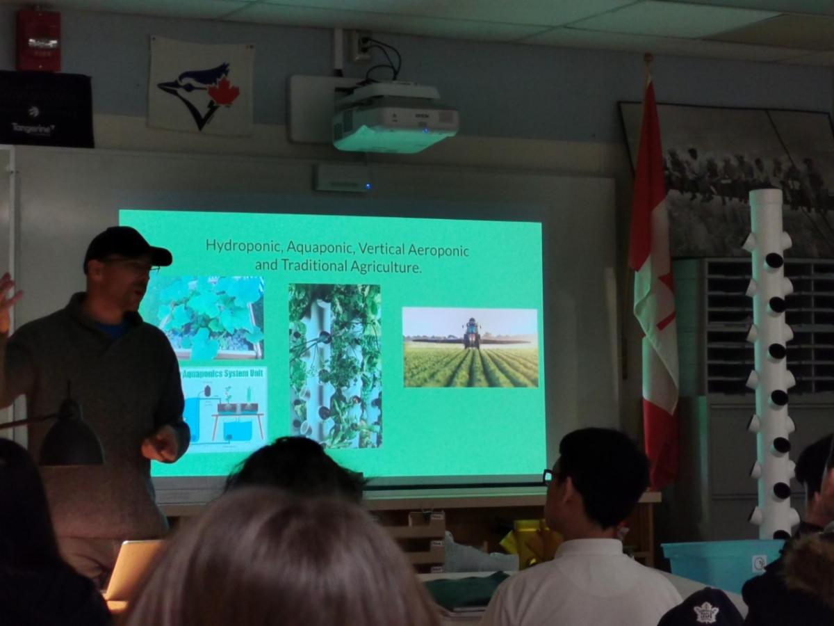 Male adult presenting to student on aeroponics gardening