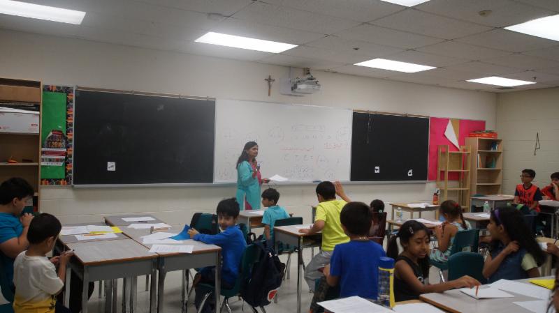 Female adults teaching elementary student another language in a classroom