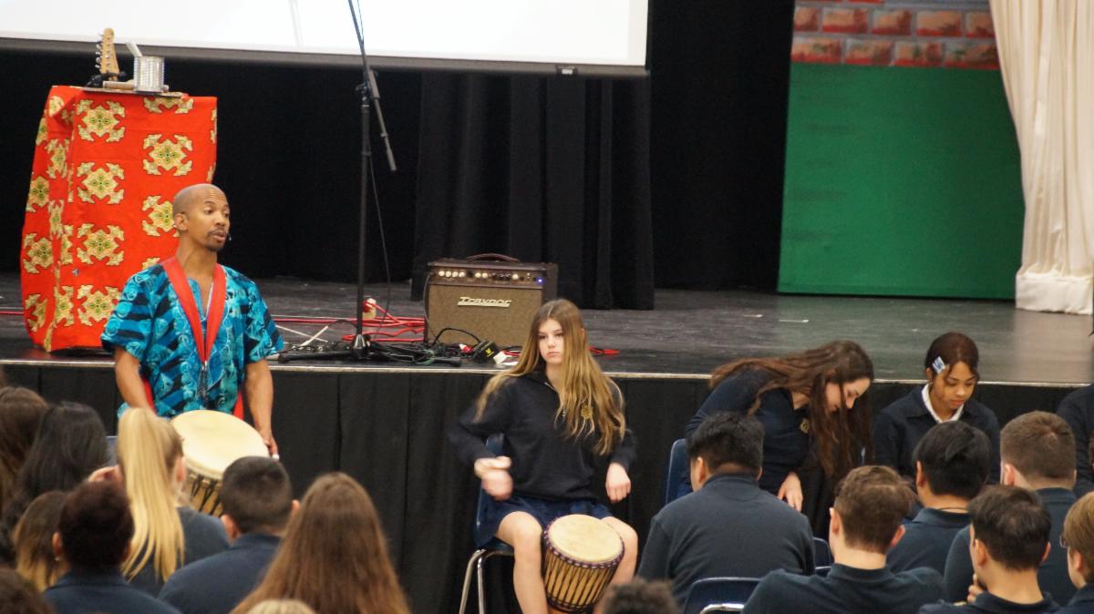 Male adult teaching students how to drum.