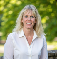 Dianna Hansen Directora Ejecutiva de la CODSN en fotografia con una blusa blanca afuera con arboles verdes atras