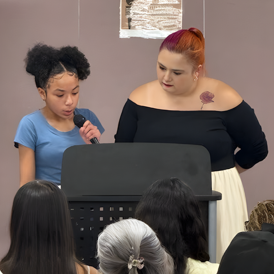 Student speaking at a podium with a teacher during the NJHS ceremony