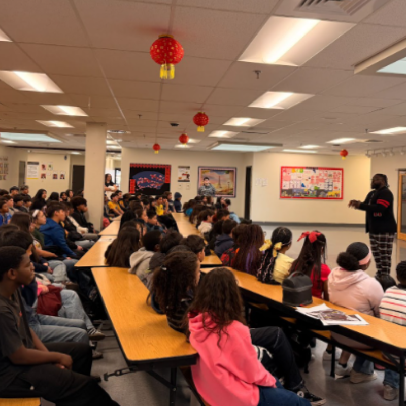 Middle school students sitting in a cafeteria walking a presentation