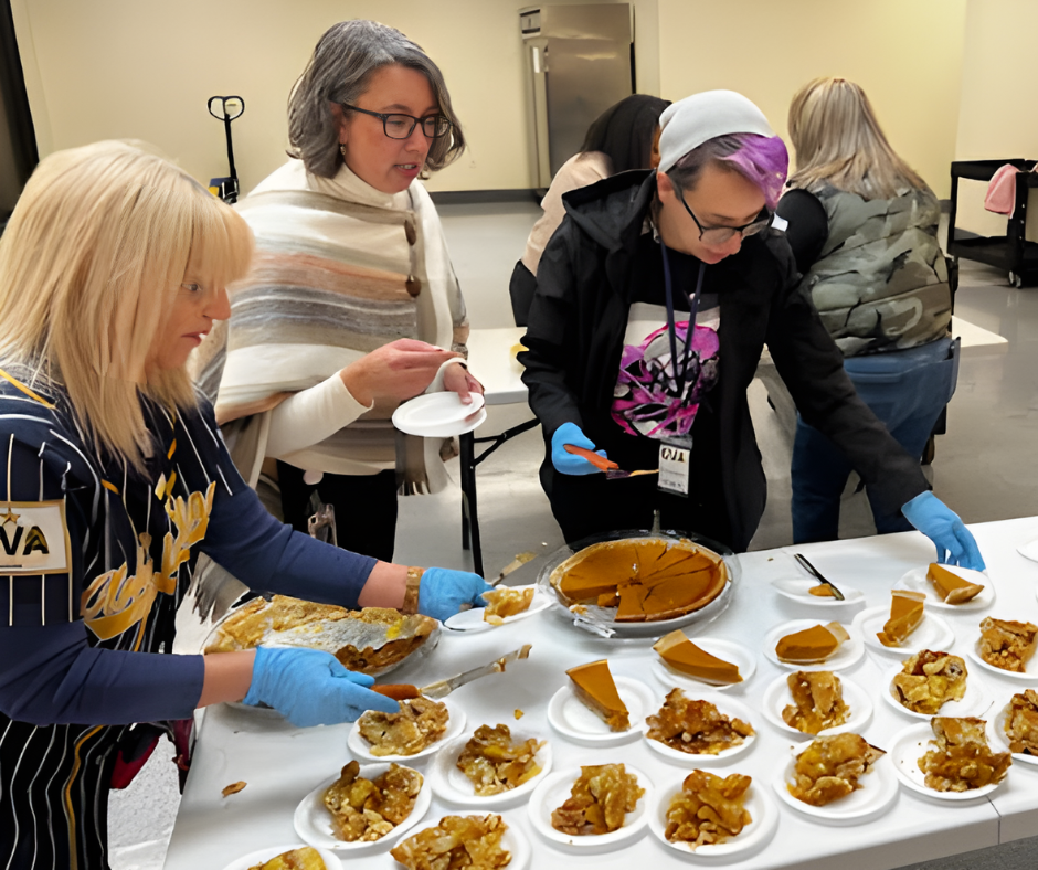 Staff members and volunteers serving slices of pie on a white table
