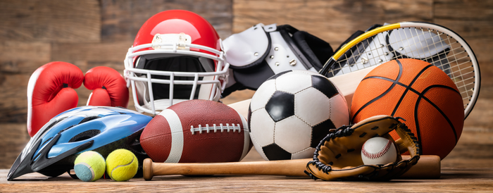 Sporting equipment in a pile on a wood floor