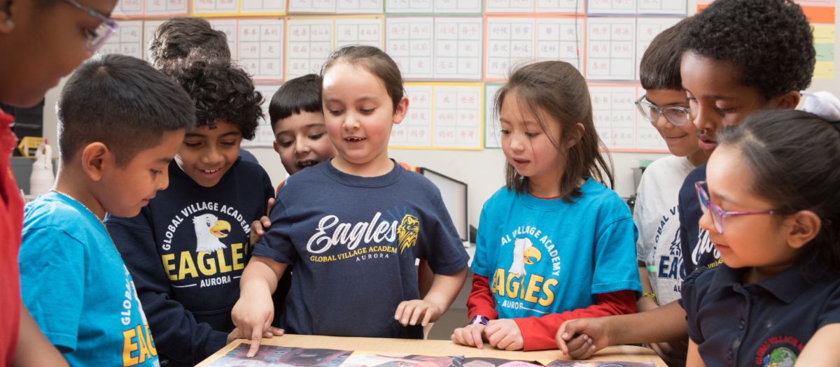 GVA Aurora students surrounding a desk and pointing to items