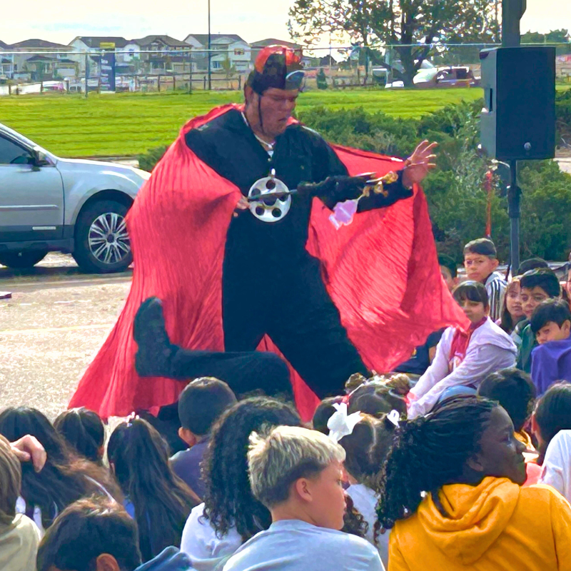 Red-caped performer acting in Shakespeare in the parking lot