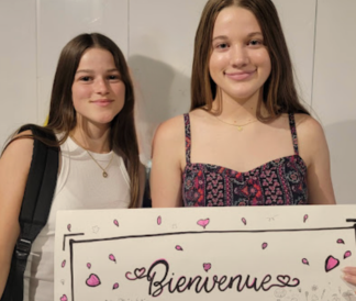 Two students holding a Bienvenue sign