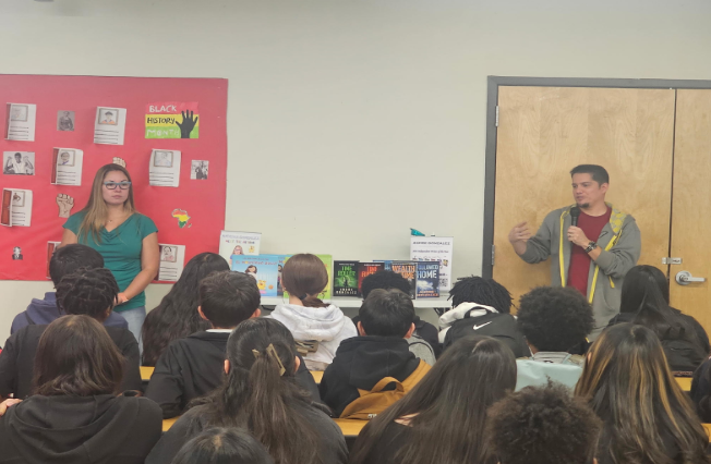 Two artists talking in front of a group of middle school students