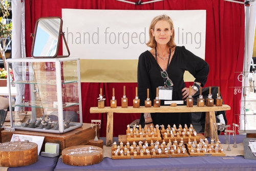 Attractive female artisan in her sterling silver jewelry booth at a crafts fair with rings_ necklaces_ bracelets_ and other accessories