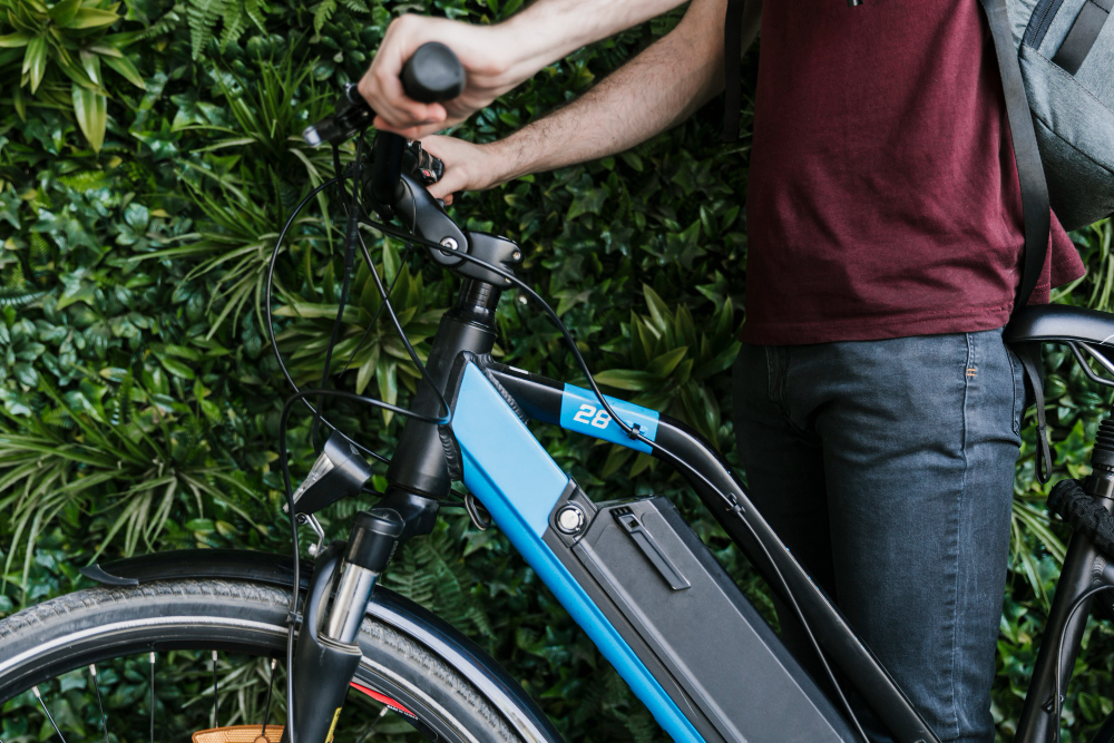 Photo of man holding handlebars of a blue e-bike